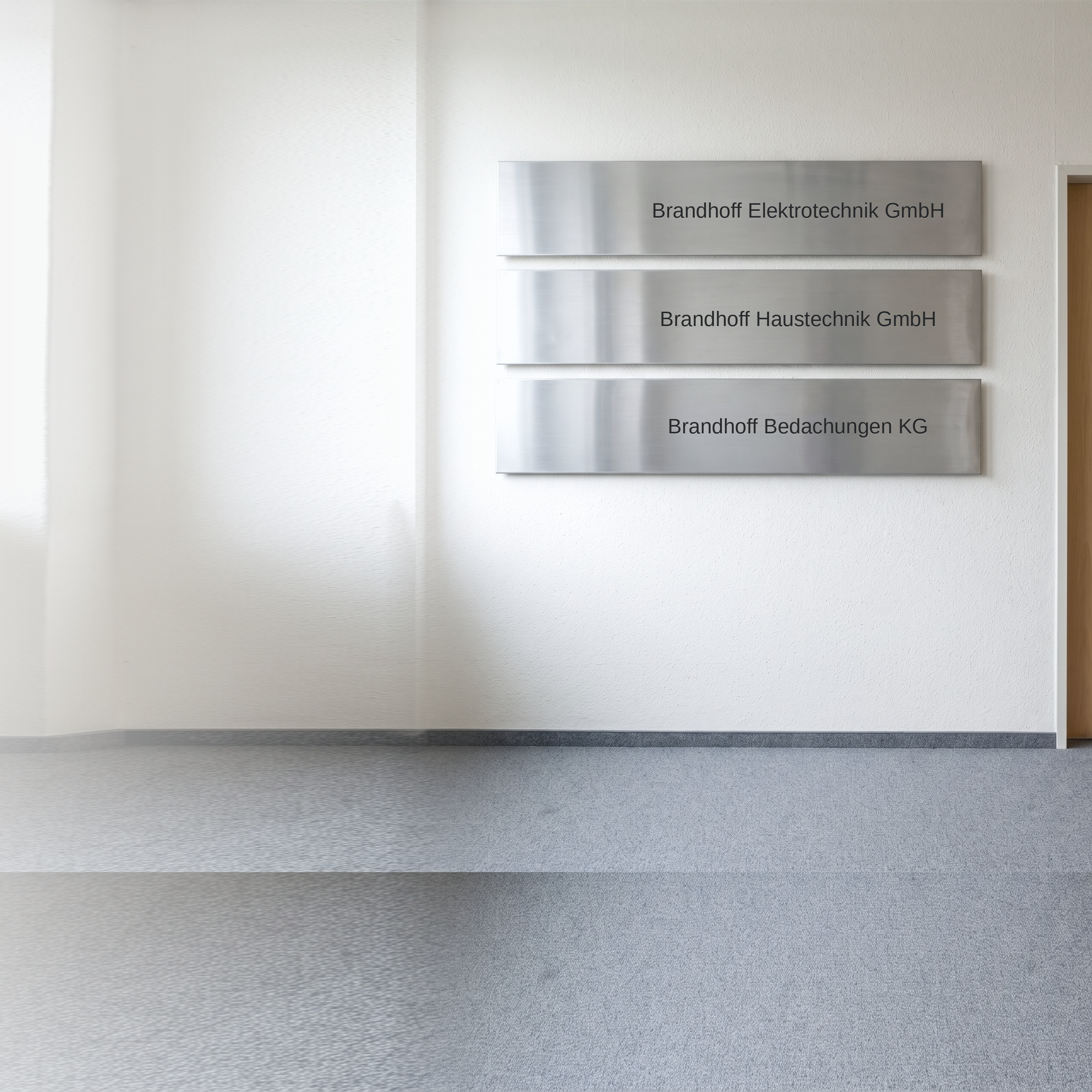 Foto einer Bürotür im Betriebsgebäude: an der Wand daneben hängen drei Firmenschilder aus gebürstetem Stahl übereinander, graviert mit Brandhoff Elektrotechnik GmbH, Brandhoff Haustechnik GmbH und Brandhoff Bedachungen KG — drei Firmen, ein Name
